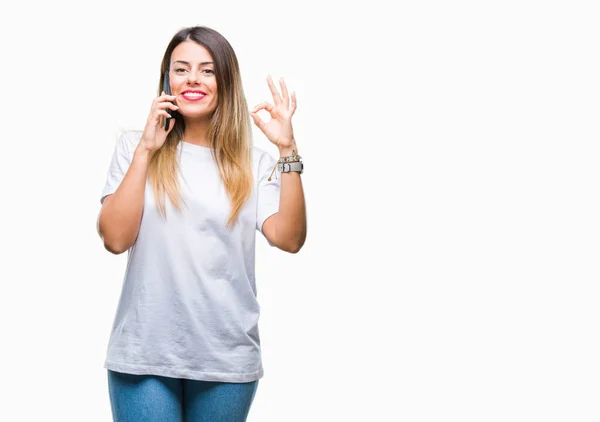 若くてきれいな女性話す通話優秀なシンボルの指で サインをして孤立の背景にスマート フォンを使用して — ストック写真