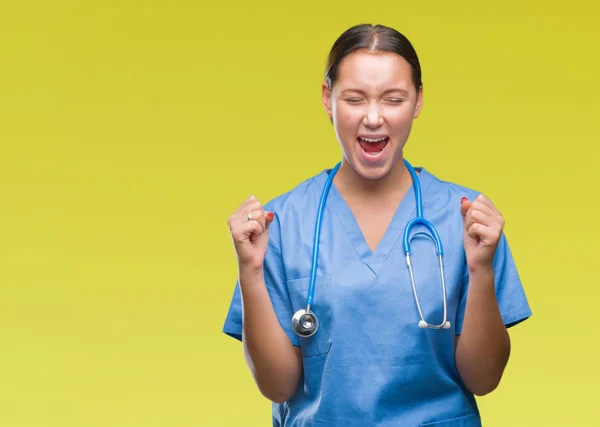 腕の成功のために興奮して孤立した背景に医療制服を着て若い白人医師女性は祝う勝利笑顔を発生します 勝者の概念 — ストック写真