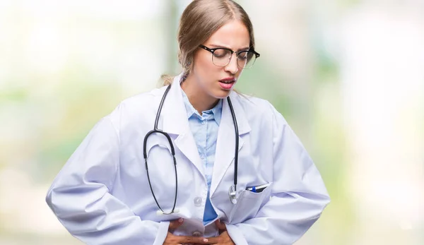 Beautiful young blonde doctor woman wearing medical uniform over isolated background with hand on stomach because indigestion, painful illness feeling unwell. Ache concept.