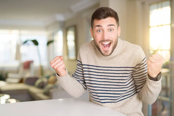 Genç yakışıklı adam evde geçirilen silahlarla şaşırmış ve başarı için hayran kutluyor ve gözleri açık. Kazanan kavramı.