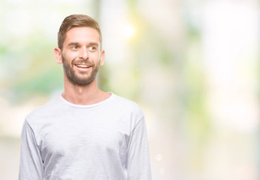 Yakışıklı delikanlı uzak tarafına yüzünde, doğal ifade gülümseme ile seyir izole arka plan üzerinde. Kendine güvenen gülüyor.