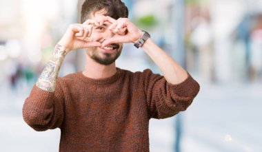 İzole arka plan yaparken kalp şekli el ve parmak işareti seyir gülümseyen ile üzerinde kış kazak giyen genç yakışıklı adam