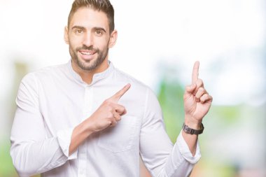 Gülümseyen ve iki elleri ve parmakları ile tarafına işaret kamera bakarak arka plan üzerinde genç iş adamı izole.
