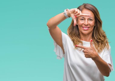 Orta yaş İspanyol kadın kıdemli elle yapma çerçeve ve parmakları ile mutlu yüz gülümseyen izole arka plan üzerinde. Yaratıcılık ve Fotoğrafçılık kavramı.
