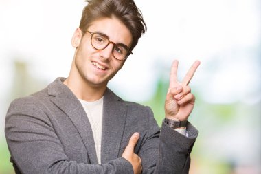 Mutlu yüz zafer işareti yaparken kameraya göz kırpıyor ile gülümseyen izole arka plan üzerinde gözlük takan genç iş adamı. İki numaralı.