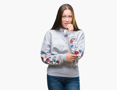 Stresli ve gergin elle çivi ısırma ağzına bakarak izole arka plan üzerinde kulaklık giyen genç güzel beyaz öğrenci kadın. Anksiyete sorunu.