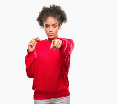 Genç afro Amerikalı kadın üzerinde çikolata macaron yeme kamera ve size parmak ile işaret arka plan izole, el işareti, pozitif ve kendinden emin bir jest ön