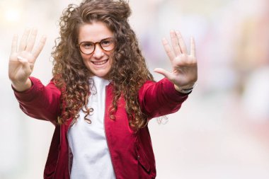 Ceket ve gözlük gösterilen ve parmakları ile işaret izole arka plan üzerinde giyen güzel esmer kıvırcık saçlı Genç kız numara 9 kendinden emin ve mutlu gülümseyerek süre.