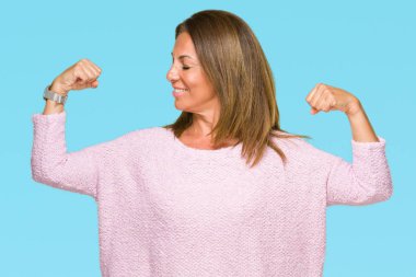 Üzerinde kış kazak giyen güzel orta yaş yetişkin kadın kol kasları gururlu gülümseyen gösterilen arka plan izole. Fitness kavramı.