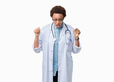 Tıbbi kat izole üzerinde giyen genç Afro-Amerikan doktor kadın arka plan işaretleme aşağı reklam, sürpriz yüz ve açık ağız gösterilen parmakları ile