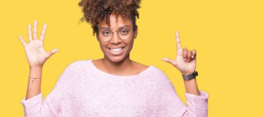 Güzel genç Afro-Amerikan kadın gözlük gösterilen ve parmakları ile işaret izole arka plan üzerinde kendinden emin ve mutlu gülümseyerek süre yedi numara.