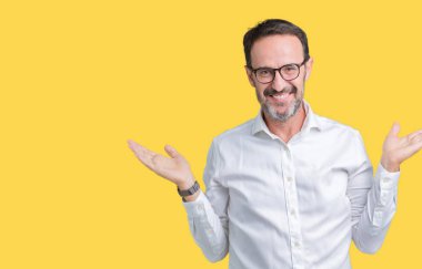 Yakışıklı orta yaş zarif üst düzey iş adamı izole arka plan gülen gösteren üzerinde her iki gözlük açık avuç içi, sunmak ve reklam karşılaştırma ve denge eller