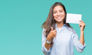 İzole arka plan üzerinde boş kartı ok işareti, başparmak ile parmak, mükemmel işareti yapıyor kocaman bir gülümseme ile mutlu tutan genç Arap kadın