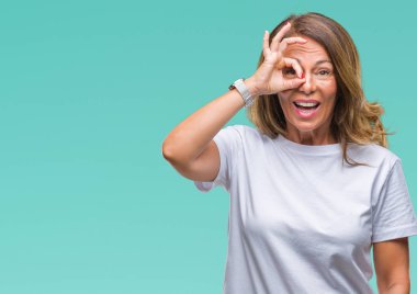 Orta yaş üst düzey İspanyol kadın gülümsüyor, parmakları ile mutlu yüz üzerinden seyir göz el ile ok jest yapıyor izole arka plan.