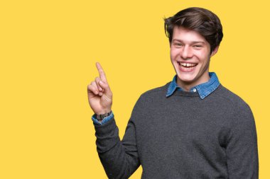 Yüzünde kocaman bir gülümseme ile izole arka plan üzerinde genç yakışıklı zarif adam kameraya bakarak yan el ve parmak ile işaret.