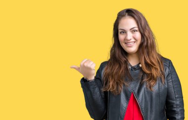 Artı boyutu genç kadın güzel üzerinde bir moda deri ceket giyiyor arka plan seyir ve başparmak yanında yukarıyı mutlu yüz ile gülümseyen izole.