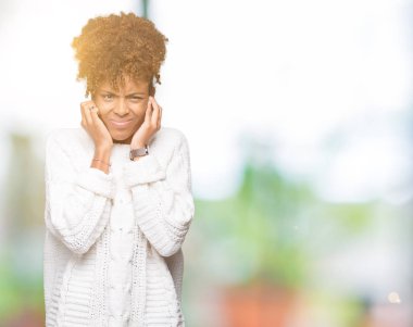 Yüksek sesle müzik gürültü rahatsız ifade parmaklarıyla kulaklarıyla kapsayan izole arka plan üzerinde kış kazak giyen güzel genç Afro-Amerikan kadın. Sağır kavramı.