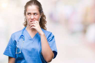 Stresli ve gergin elle çivi ısırma ağzına bakarak izole arka plan üzerinde hemşire ya da cerrah üniforma giyen genç esmer doktor kız. Anksiyete sorunu.