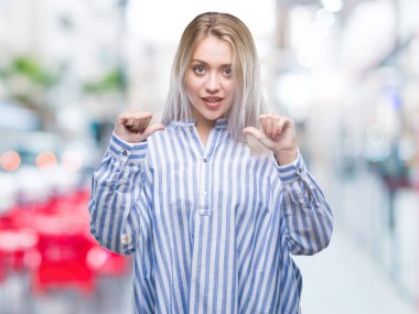 Yüzünde gülümseme ile kendinden emin görünüyorsun, kendini gururlu ve mutlu parmakları ile işaret izole arka plan üzerinde sarışın genç kadın.