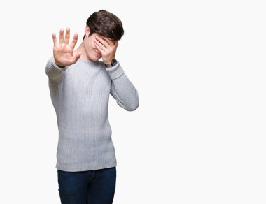 Yakışıklı delikanlı üzerinde kış kazak giyen izole elleriyle gözlerini kapsayan arka plan ve stop jest ile acı ve korku ifadesi. Utandım ve negatif kavramı.