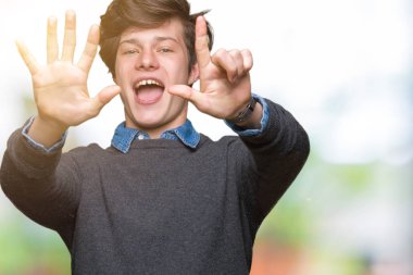 Genç yakışıklı zarif adam gösterilen ve parmakları ile işaret izole arka plan üzerinde kendinden emin ve mutlu gülümseyerek süre yedi numara.