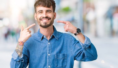 Tecrit edilmiş, güler yüzlü, kendine güvenen, parmaklarını, dişlerini ve ağzını gösteren genç yakışıklı bir adam. Sağlık kavramı.