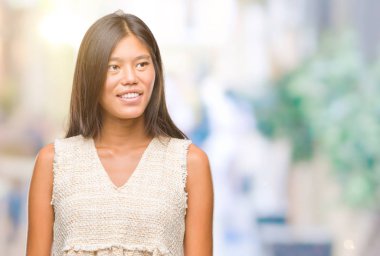 Genç Asyalı kadın uzak tarafına yüzünde, doğal ifade gülümseme ile seyir izole arka plan üzerinde. Kendine güvenen gülüyor.