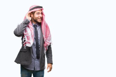 Genç yakışıklı Arap adam uzun saçlı bir işitme söylenti ya da dedikodu için dinleme kulak üzerinde el ile gülümseyen izole arka plan üzerinde keffiyeh giyiyor. Sağırlık kavramı.