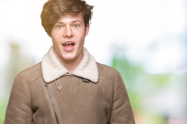 Yakışıklı delikanlı izole arka plan korkuyor ve şok sürpriz ifade, korku ve heyecan yüz üzerinden kış palto giyiyor.