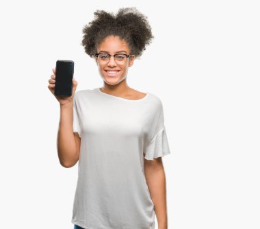 Genç güzel afro Amerikan gösteren smartphone ekran üzerinde duran ve diş gösterilen kendine güvenen bir gülümsemeyle gülümseyerek mutlu bir yüz ile izole arka plan