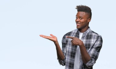 Genç Afro-Amerikan adam üzerinden hayran ve el ile sunulması ve parmak ile işaret ederken kameraya gülümseyen izole arka plan.