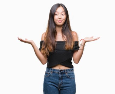 Genç Asyalı kadın yüzünden izole arka plan clueless ve şaşkın bir ifadeyle kollar ve eller kaldırdı. Şüphe kavramı.