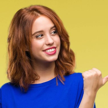 Seyir ve başparmak yanında yukarıyı mutlu yüz ile gülümseyen izole arka plan üzerinde genç güzel kadın.