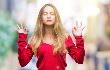 İzole arka plan üzerinde kırmızı kazak giyen genç güzel sarışın kadın dinlenmek ve gülümseyen gözlerle kapalı parmak jestle meditasyon yapıyor. Yoga kavramı.