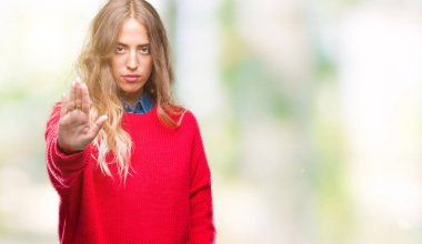 Elin avuç durağı şarkı yapıyor izole arka plan üzerinde kış kazak giyen güzel genç sarışın kadın. Negatif ve ciddi bir jest yüz ifadesiyle uyarı.