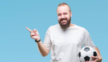 Futbol futbol topu izole arka plan üzerinde çok mutlu el ve parmak ile tarafına işaret tutan genç beyaz hipster adam