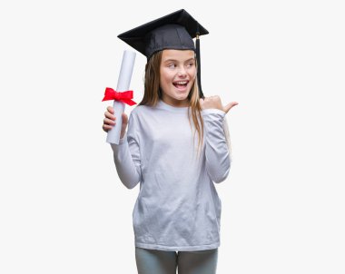 Genç güzel kız derecesi işaret ve başparmak kadar mutlu yüz gülümseyen tarafı ile gösteren izole arka plan üzerinde tutarak lisansüstü şapkası