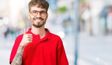 Hareketi el ile mutlu yaşasın yapıyor izole arka plan üzerinde gözlük takan yakışıklı delikanlı. Başarı gösteren kameraya bakarak ifade onaylama.