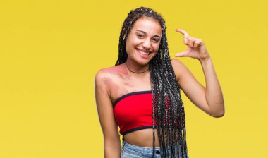 Genç örgülü saç Afrika kökenli Amerikalı pigmentasyon ile izole arka plan gülümseyen ve boyutu işaret parmaklı ararken ve kamera işi el ile kendinden emin eller üzerinde Doğum işareti leke. Ölçü kavramı.