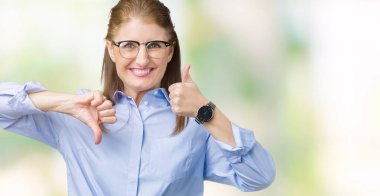 Güzel orta yaş olgun iş kadını izole arka plan yapmaya başparmak yukarı ve aşağı, anlaşmazlık ve anlaşma ifade üzerinde gözlük takıyorum. Deli çatışma