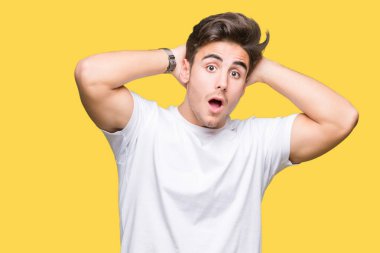 T-shirt üzerinde arka plan deli izole ve ile korkuttu beyaz giyen genç yakışıklı adam kafasına, korkmuş ve şaşırmış şok açık ağız ile eller