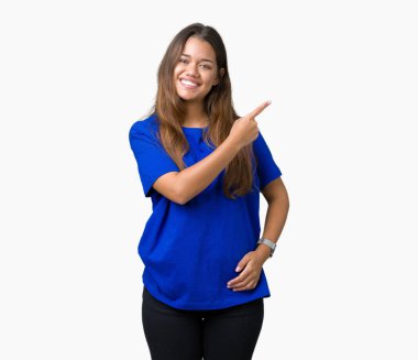 İzole arka neşeli bir gülümseme ile el ve parmak kadar yan yüzünde mutlu ve doğal ifade ile işaret yüz üzerinde mavi t-shirt giyen genç güzel esmer kadın