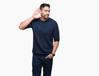 Bir işitme söylenti ya da dedikodu için dinleme kulak üzerinde el ile gülümseyen izole arka plan üzerinde kazak giyen genç yakışıklı adam. Sağırlık kavramı.