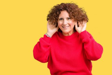 Güzel orta ager üst düzey kadın kırmızı kış kazak her ikisi de dinliyoruz izole arka plan üzerinde kulak jest, dedikodu için meraklı eller. İşitme sorunu, sağır