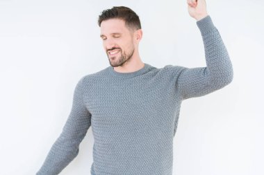 İzole arka plan dans mutlu ve neşeli, hareketli rahat ve kendinden emin müzik gülümseyen üzerinde rahat kazak giyen genç yakışıklı adam