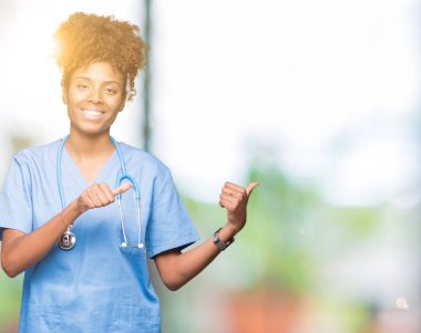 Genç Afro-Amerikan doktor kadın izole arka plan yüzünden kendinden emin gülümseyen arkasından el ve kadar başparmak ile işaret