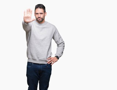 Elin avuç durağı şarkı yapıyor izole arka plan üzerinde sweatshirt giyen genç yakışıklı adam. Negatif ve ciddi bir jest yüz ifadesiyle uyarı.