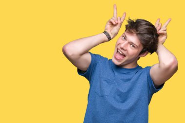 Neşeli gülümseyen izole arka plan tavşan kulakları, komik ve çılgın baş parmaklar ile poz üzerinde mavi t-shirt giyen genç yakışıklı adam