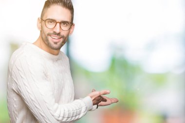 Açık el ile doğal gülümseyen girmek için davet izole arka plan üzerinde gözlük takan genç yakışıklı adam