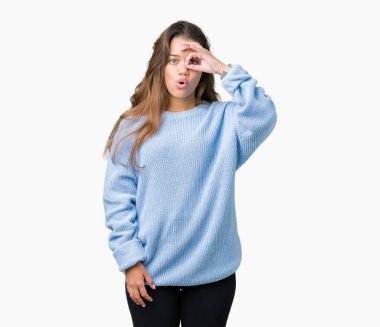 Sürpriz yüz, göz parmaklarının arasından seyir ile ok jest yapıyor izole arka plan üzerinde mavi kış kazak giyen genç güzel esmer kadın şok. İmansız ifade.